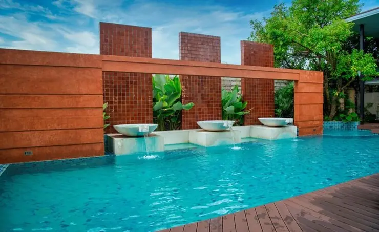 Commercial pool with rust-toned screen wall and planters by Heavenly Outdoor in Galveston, TX