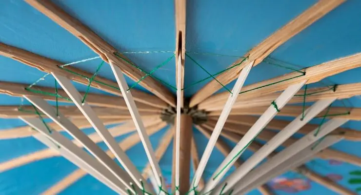 Underside of an adjustable louvered roof with slats fanned out against the sky